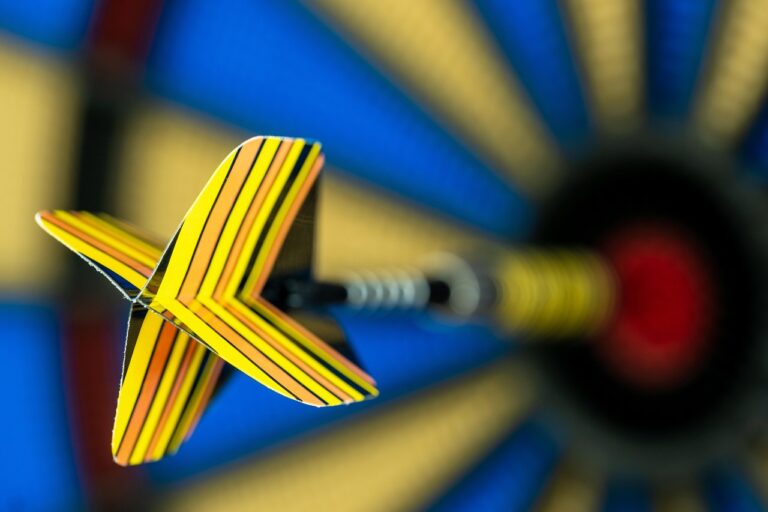 Darts-Spieler wirft präzise Pfeile neben modernem Mähroboter im Garten